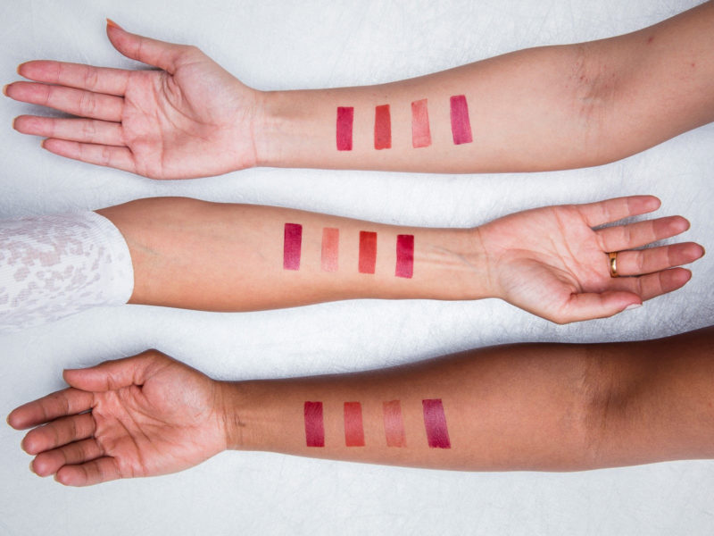 Three arms laid one above the other, with lipstick test strips in various different shades of pink. The image is there to signify clean beauty and how it is better for your skin.